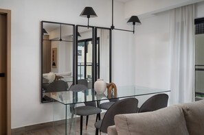 A modern dining area with a glass table, chairs, and a large mirror.