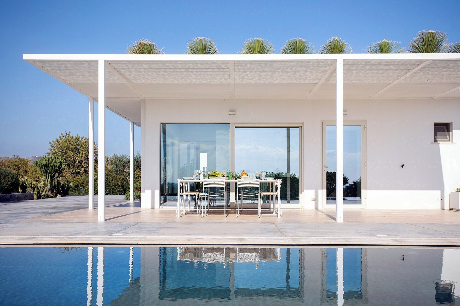 A modern outdoor dining area with a pool in the foreground.