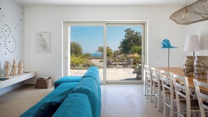 Una sala de estar moderna con un amplio ventanal corredera que da a un patio exterior.