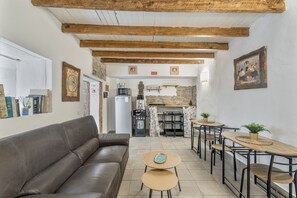 Un salon chaleureux avec un canapé en cuir marron, des tables en bois et une cuisine en arrière-plan.
