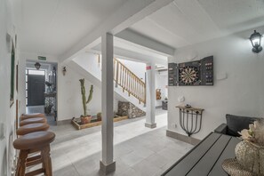 A spacious lobby with a staircase, a dartboard, and a cactus plant.
