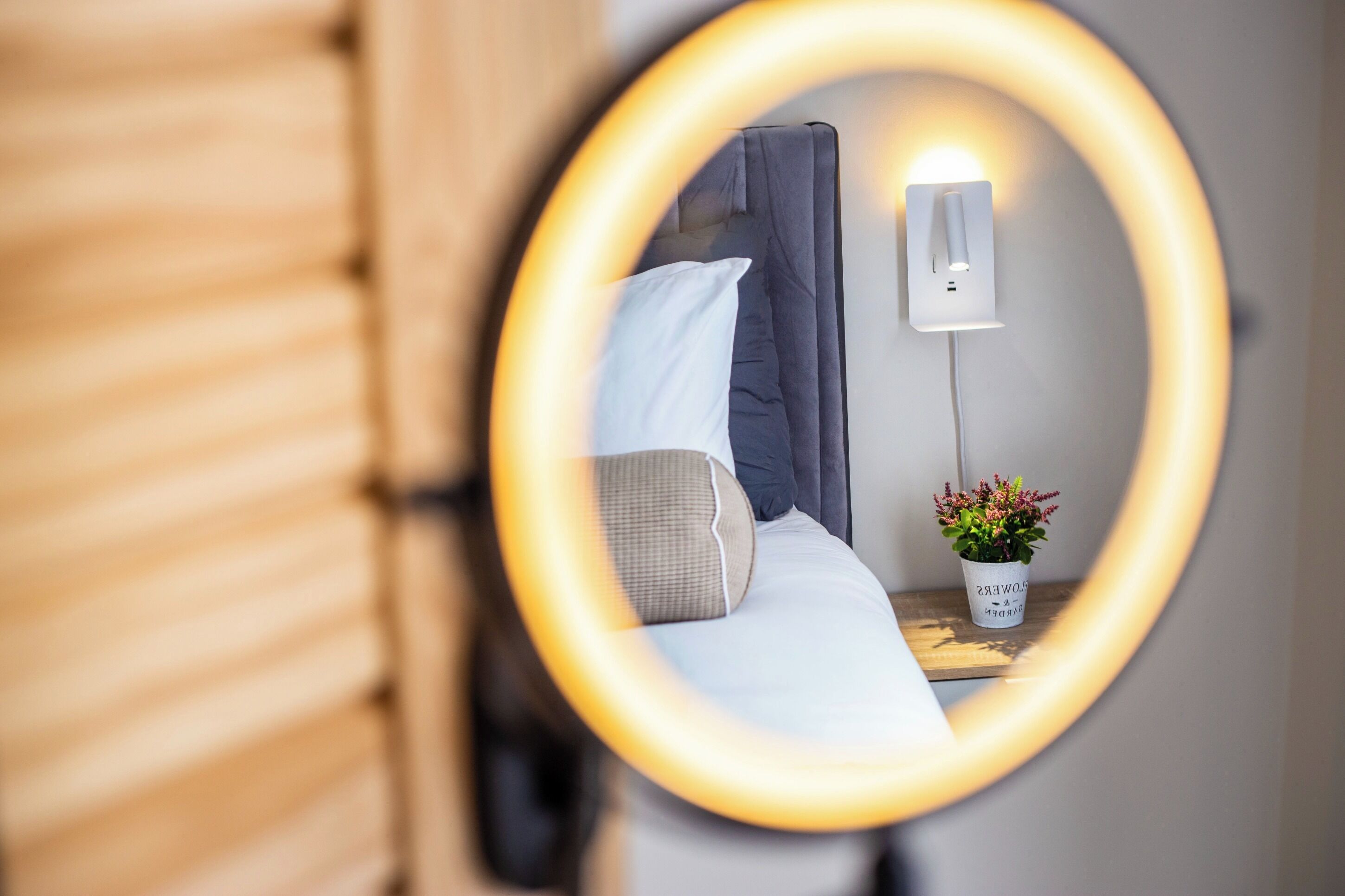 Un dormitorio con una cama, una mesita de noche, un enchufe y una planta en maceta.
