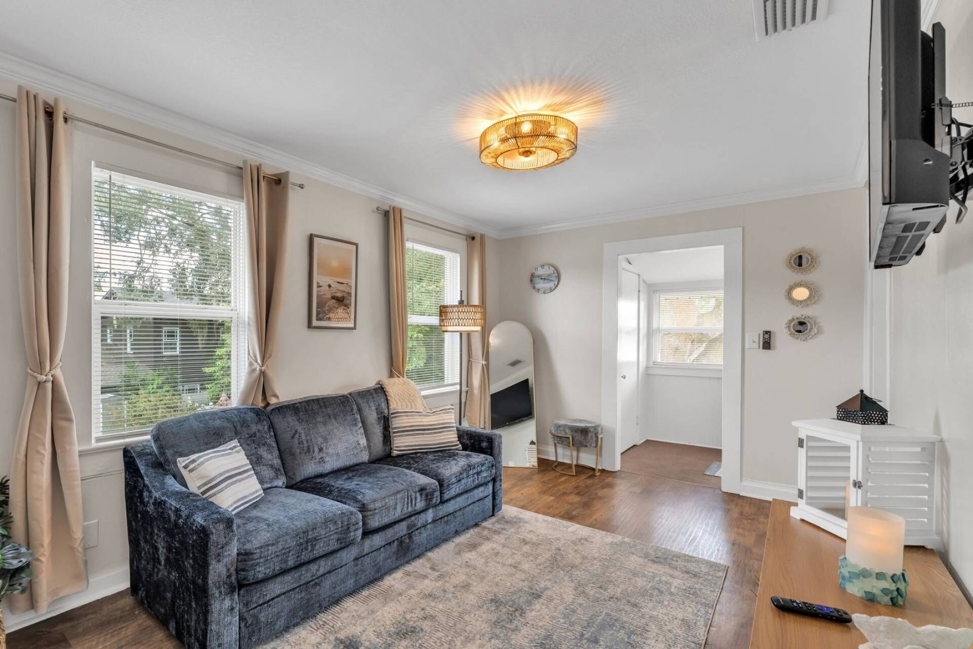 A living room with a blue sofa, a rug, a ceiling light, and a door leading to another room.