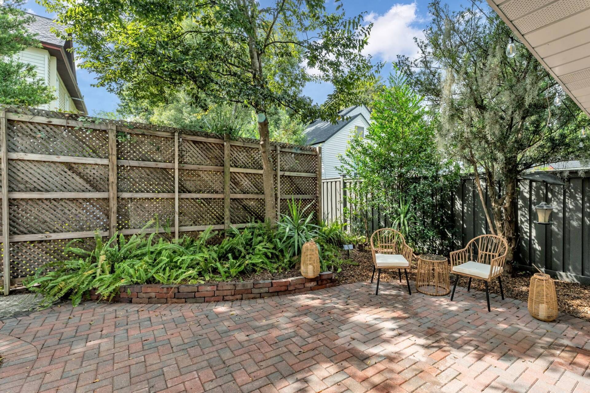 Une terrasse avec un sol en briques, une clôture en bois et du mobilier d’extérieur.