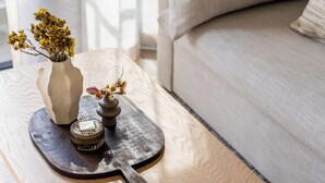 A wooden coffee table with a vase of dried flowers, a decorative bowl, and a small candle. - The York | Designer CBD Apartment (Cape Town)