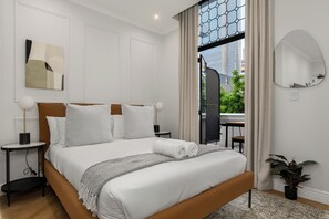 A modern hotel room with a large bed, a view of the city, and a potted plant. - Modern Venetian Hideaway | Mountain and City Views (Cape Town)