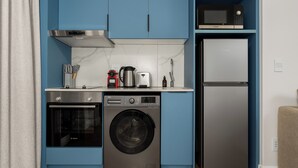 Eine kleine Küche mit einer Bosch Waschmaschine, einer Mikrowelle und einem Kühlschrank.