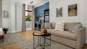 Ein modernes Wohnzimmer mit einem beigefarbenen Sofa, einem runden Couchtisch und einer Küchenzeile im Hintergrund.