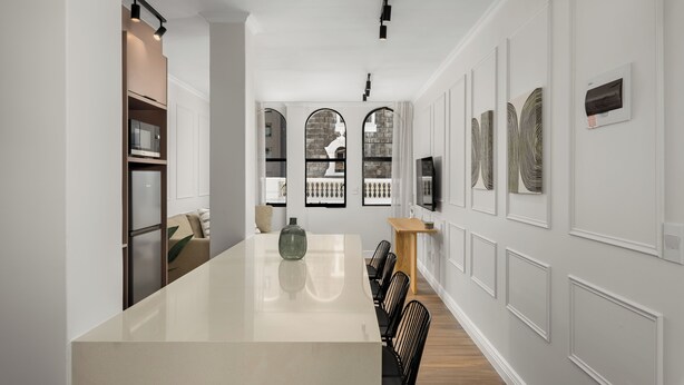 Una cocina moderna con una isla grande, electrodomésticos integrados y vistas a través de ventanas de arco.