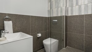 Un baño moderno con un lavabo blanco, un inodoro y una cabina de ducha de vidrio.