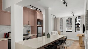 Una cocina moderna con una isla central, taburetes de bar y un área de comedor con vista a la ciudad.