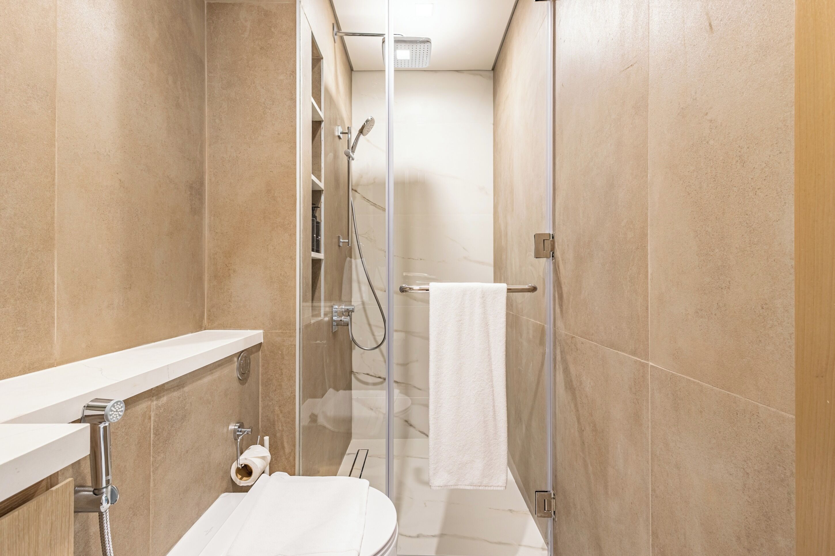 Un baño moderno con ducha de vidrio, lavamanos blanco y un inodoro.
