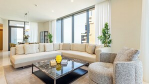 Ein modernes Wohnzimmer mit einem Ecksofa, einem Glastisch und einem grauen Sessel.