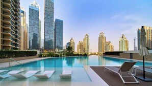 Ein Pool auf dem Dach mit Liegestühlen und einer Skyline im Hintergrund.