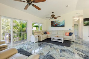 A spacious living room with a large sectional sofa, a coffee table, and a ceiling fan.