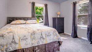 Un dormitorio con cama, cómoda y ventana con cortinas.