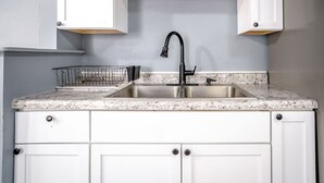 Una cocina con armarios blancos, encimera de granito, pileta de acero inoxidable y grifo negro.