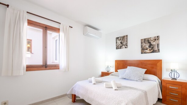 A bedroom with a bed, a window with curtains, a nightstand, and wall art. - Holiday Home 'Casa Guillermo' with Mountain View, Wi-Fi and Air Conditioning (Pollensa)