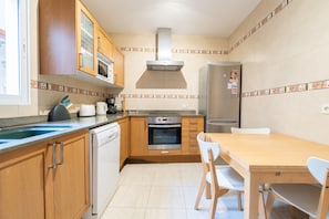 A kitchen with wooden cabinets, a stainless steel oven, a microwave, and a refrigerator.
