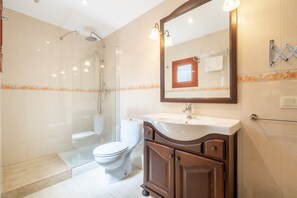 Ein Badezimmer mit Duschkabine, Toilette, Waschbecken mit Spiegel und Handtuchhalter.