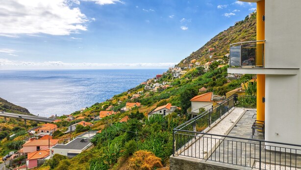 Zona residencial costera con casas en una colina, cielo despejado y vistas al mar.
