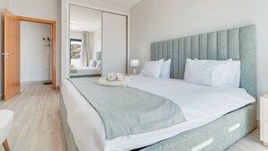 Una habitación de hotel moderna con una cama grande, un espejo y vistas al exterior.