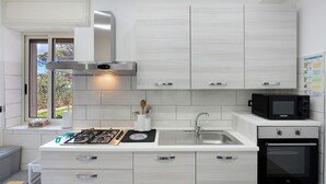 Une cuisine moderne équipée d’une cuisinière à gaz, d’un four à micro-ondes, d’un four traditionnel et d’une fenêtre donnant sur un paysage verdoyant.