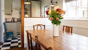 A dining area with a wooden table and chairs, a vase of flowers, and a checkered floor. - Easter Cottage - Central Rye, Effortless Chic! | Pass the Keys (Rye)