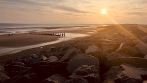 A rocky beach with a wooden pier extending into the sea, under a sunset sky. - Easter Cottage - Central Rye, Effortless Chic! | Pass the Keys (Rye)