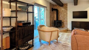 A cozy living room with a fireplace, a sofa, and a TV mounted on the wall. - Stunning Mtn Condo - Prime Location, Walk to Ski Lifts & Main Street! (Breckenridge)