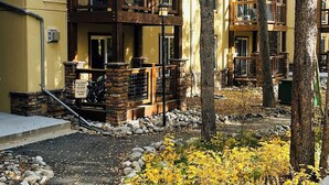 A multi-story building with balconies, a stone entrance, and a surrounding natural landscape. - Stunning Mtn Condo - Prime Location, Walk to Ski Lifts & Main Street! (Breckenridge)