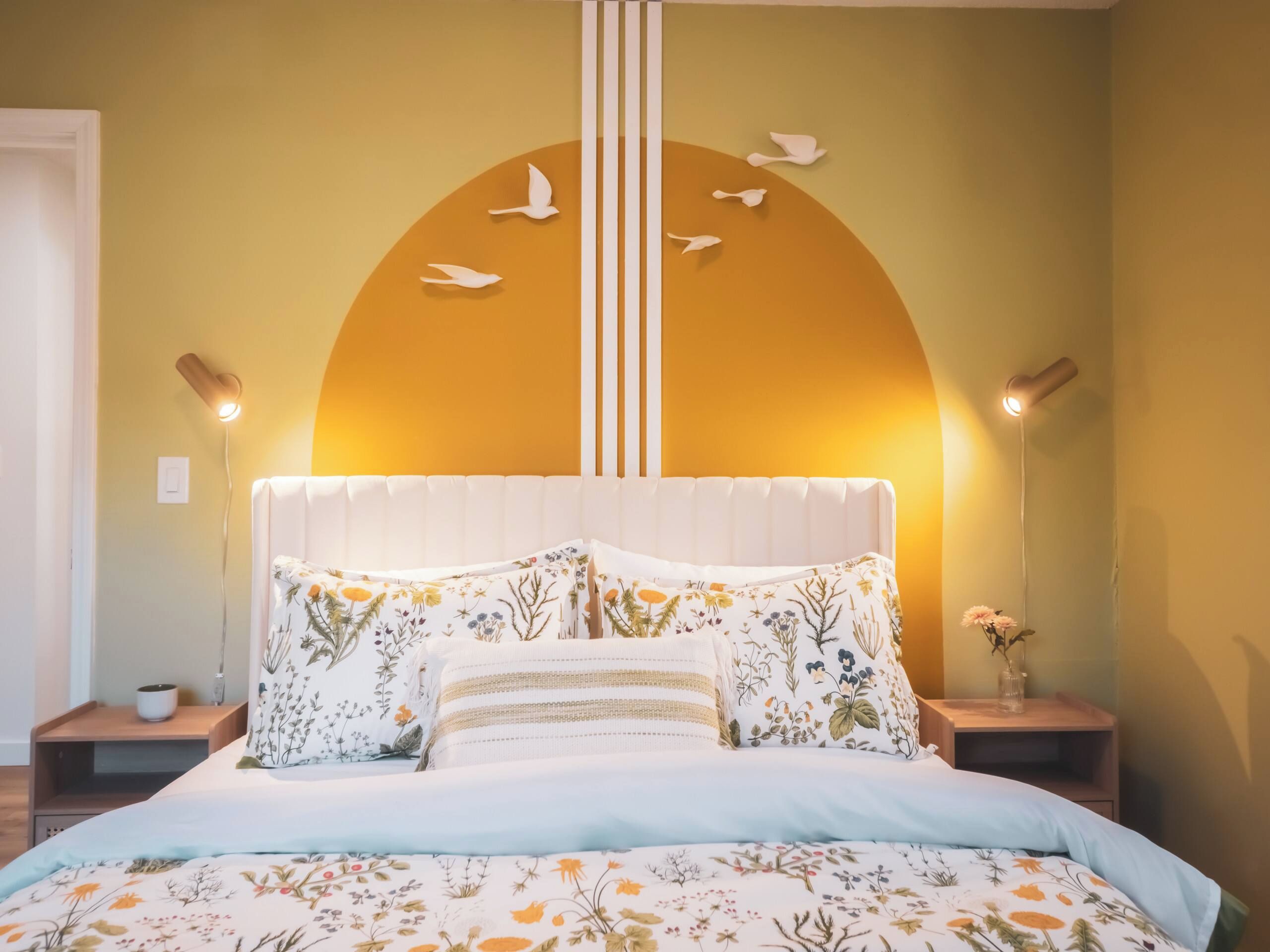 Une chambre à coucher comprenant un lit, des oreillers, une table de chevet, une horloge murale et un élément décoratif mural.