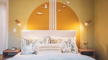 Une chambre à coucher comprenant un lit, des oreillers, une table de chevet, une horloge murale et un élément décoratif mural.