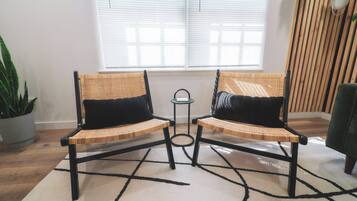 Two wicker chairs with black cushions, a small table, and a potted plant in a corner.