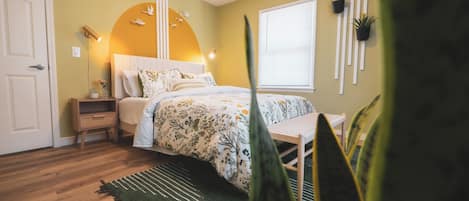 Een slaapkamer met een bed, nachtkastje, lamp en een raam met zonwering.