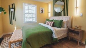 Un dormitorio con cama, mesita de noche y ventana.