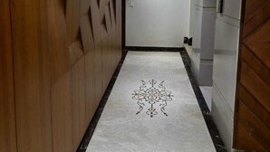 Un couloir avec un mur en bois, une porte blanche et un sol à motifs.