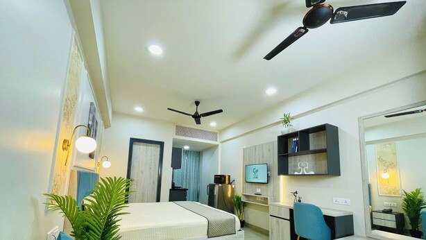 Une chambre d’hôtel moderne équipée d’un lit, d’un canapé, d’un bureau et d’un ventilateur de plafond.