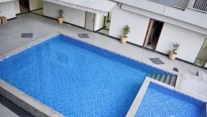 Une piscine rectangulaire dont le bord est recouvert de carreaux, entourée d’une terrasse en béton.