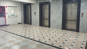Un couloir avec trois ascenseurs et une porte sur laquelle est apposée une pancarte.