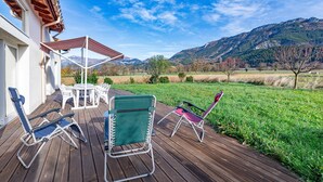 A deck with outdoor furniture, a table, and a view of a mountainous landscape.