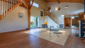 A spacious interior with a wooden staircase, a large window, and a modern chair.