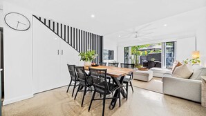Eine moderne Küche mit einem Holzespeisetisch, schwarzen Stühlen und einer Treppe mit schwarz-weißen Streifen.