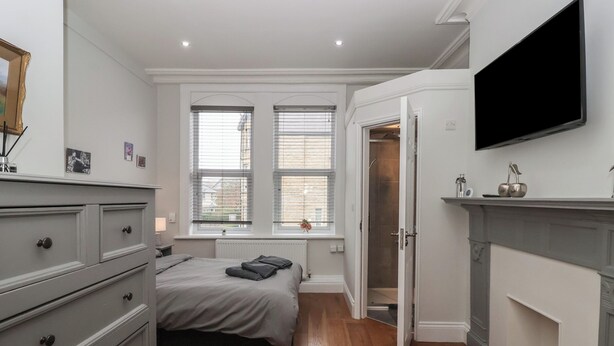 Un dormitorio con cama, cómoda, televisión y chimenea.
