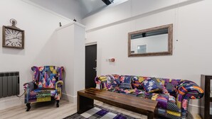Un saló modern amb un sofà de colors, un butac armchair estampat i una taula baixa de fusta.