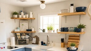 Una cocina con armarios azules, un lavamanos blanco y repisas de madera sobre la encimera.