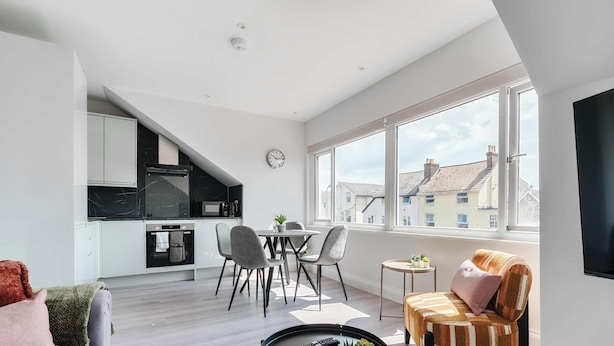 A modern apartment with a kitchen, dining area, and a sofa.