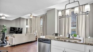 Una cocina moderna con lavavajillas, armarios blancos y encimera de granito.