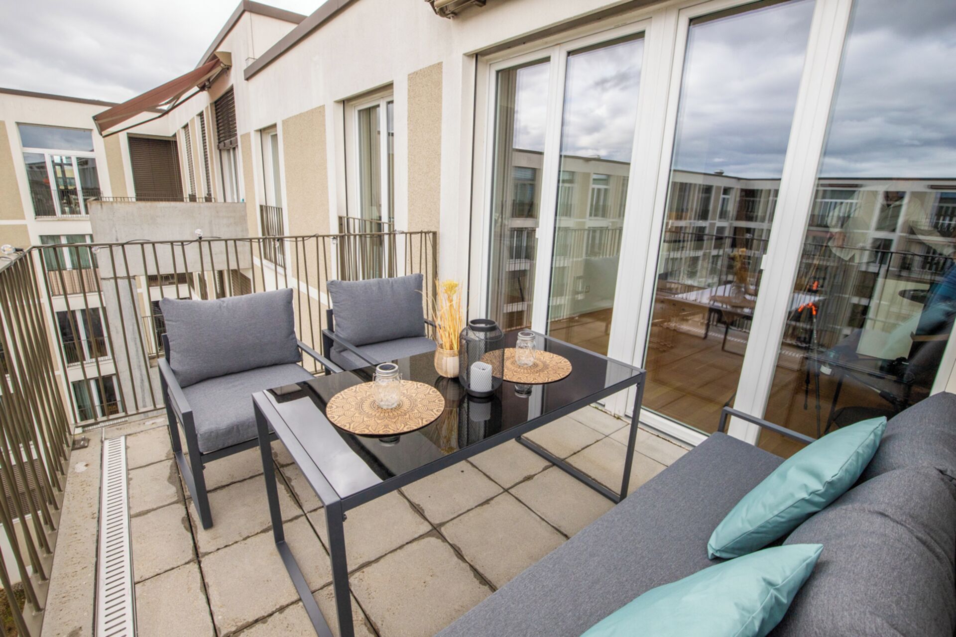 A balcony with a sofa, chairs, and a table with decorative items.