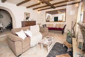 A living room with a beige sofa, a wooden coffee table, a red sofa, and a fireplace.